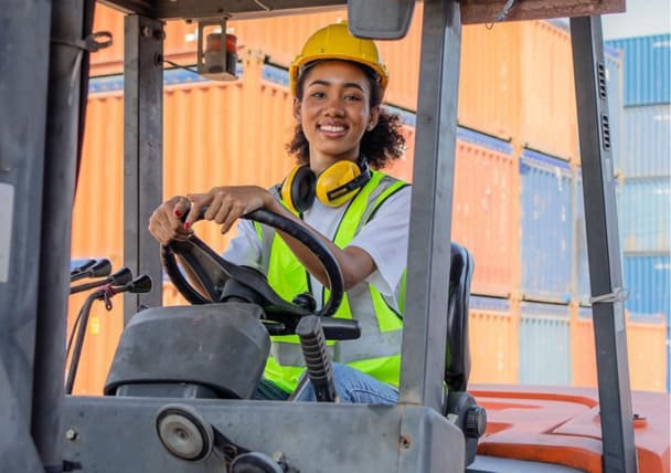 Vrouw in veiligheidskleding op heftruck als voorbeeld van veilig werken na een goede RI&E